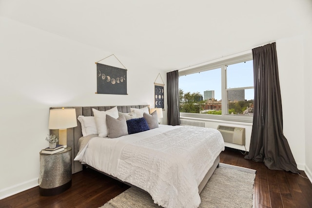 bedroom with wood-type flooring, baseboards, and a wall unit AC