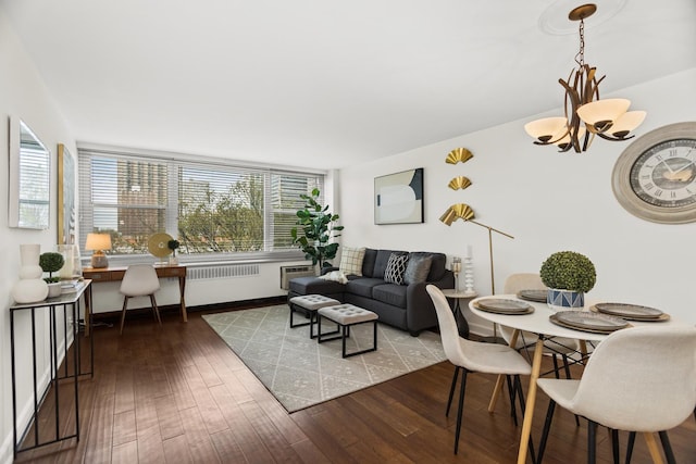 living area featuring a chandelier, wood-type flooring, an AC wall unit, baseboards, and radiator