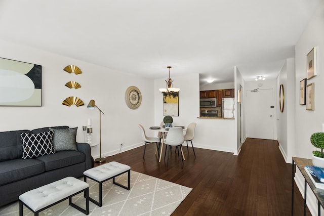 living room with dark wood-style flooring, a chandelier, and baseboards