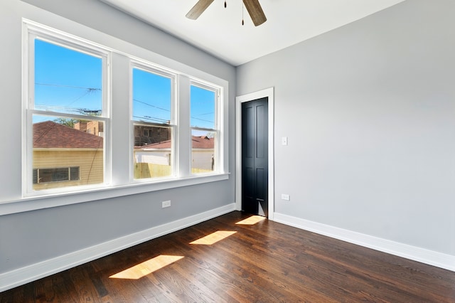 unfurnished room featuring baseboards, ceiling fan, and dark wood-style floors