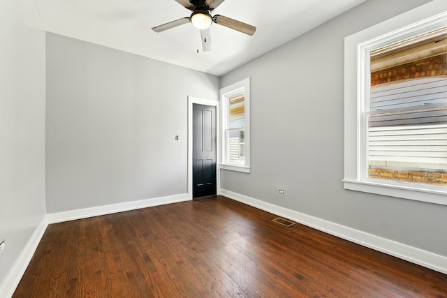 spare room featuring ceiling fan, baseboards, visible vents, and dark wood finished floors