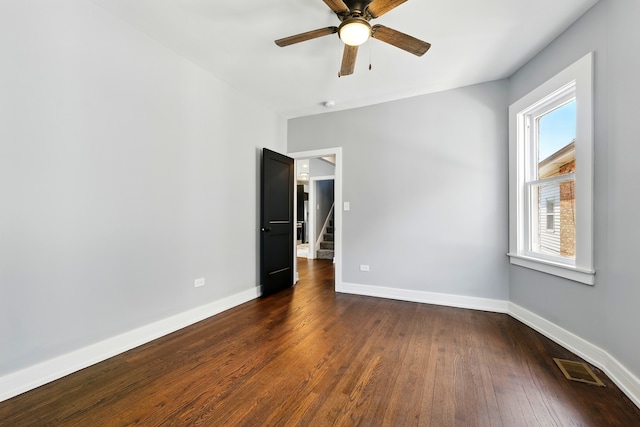 spare room with a ceiling fan, baseboards, visible vents, and dark wood-style floors