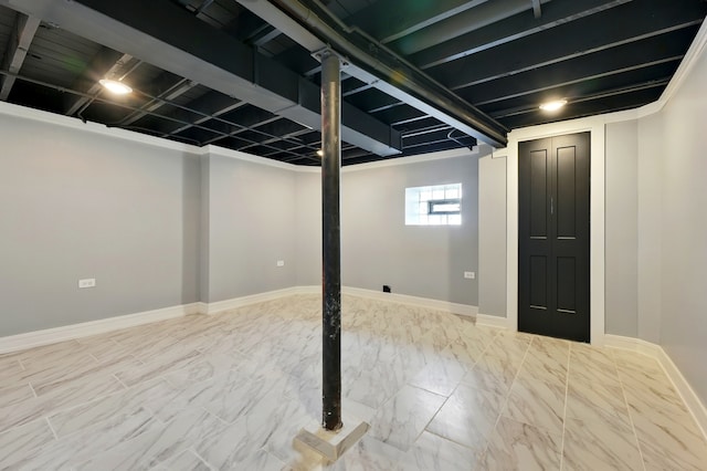 below grade area with baseboards and marble finish floor