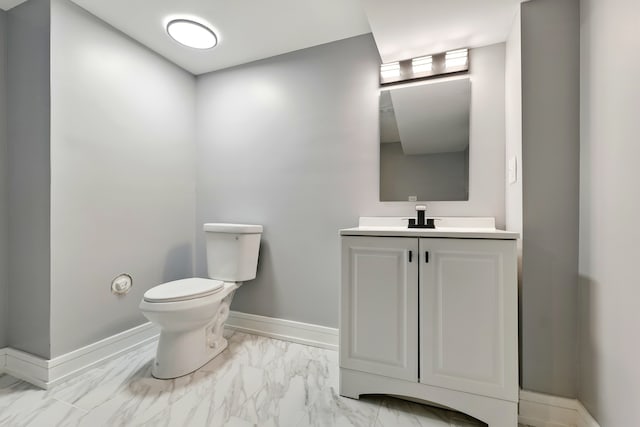 half bathroom featuring vanity, toilet, marble finish floor, and baseboards