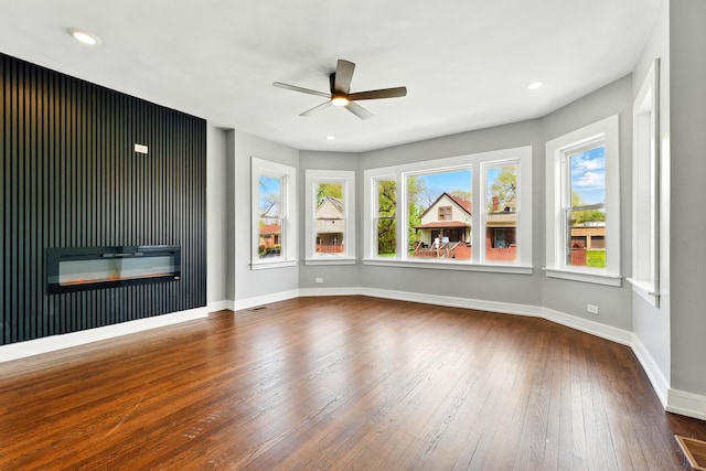 unfurnished living room featuring hardwood / wood-style floors, recessed lighting, a ceiling fan, baseboards, and a glass covered fireplace