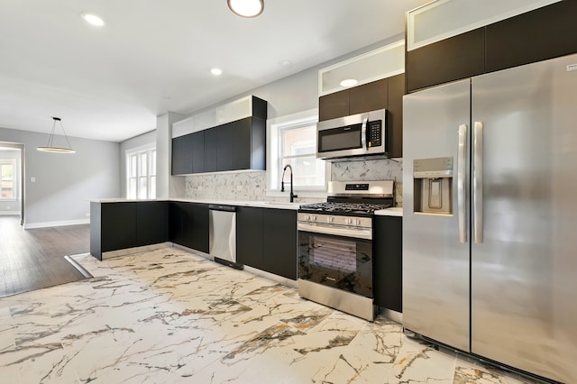 kitchen featuring light countertops, appliances with stainless steel finishes, a sink, and backsplash
