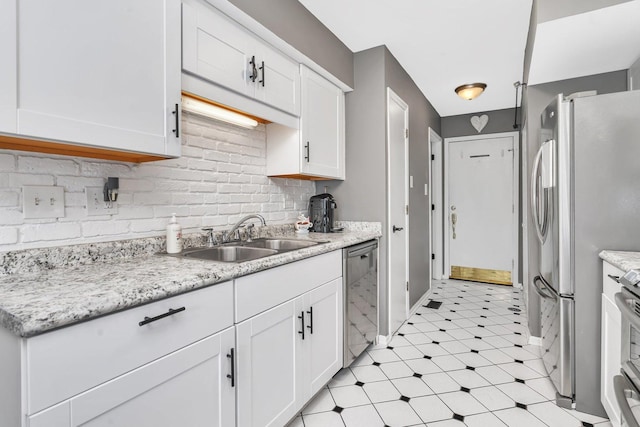 kitchen featuring decorative backsplash, white cabinets, appliances with stainless steel finishes, and a sink