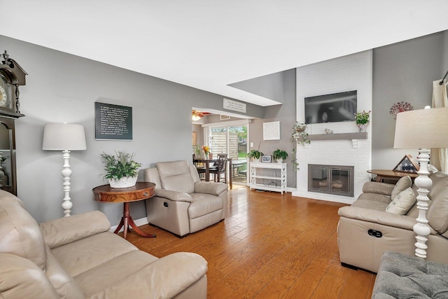 living room featuring a brick fireplace and wood finished floors
