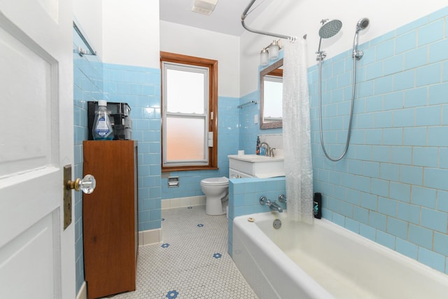 full bath with tile walls, toilet, wainscoting, tile patterned flooring, and shower / bathtub combination with curtain