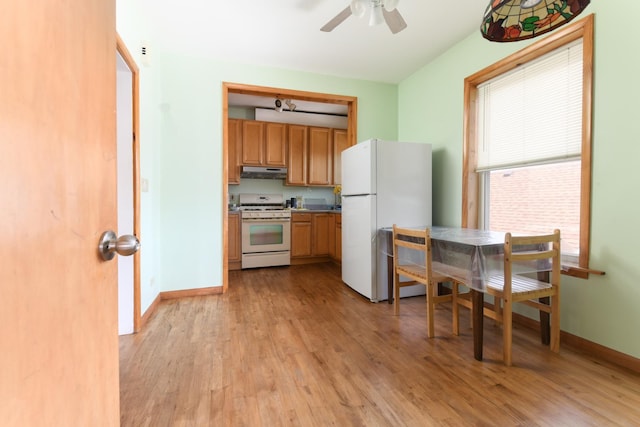 kitchen featuring white appliances, light wood-type flooring, under cabinet range hood, a ceiling fan, and baseboards