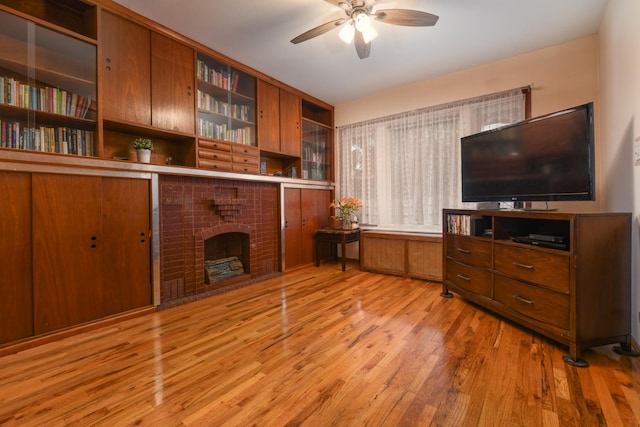 living room with light wood-style flooring, a ceiling fan, and a fireplace