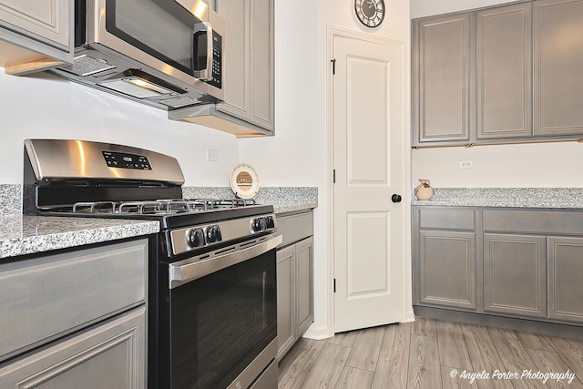 kitchen with gray cabinetry, appliances with stainless steel finishes, and light wood-style flooring