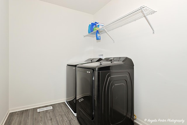 laundry area featuring laundry area, independent washer and dryer, visible vents, wood finished floors, and baseboards