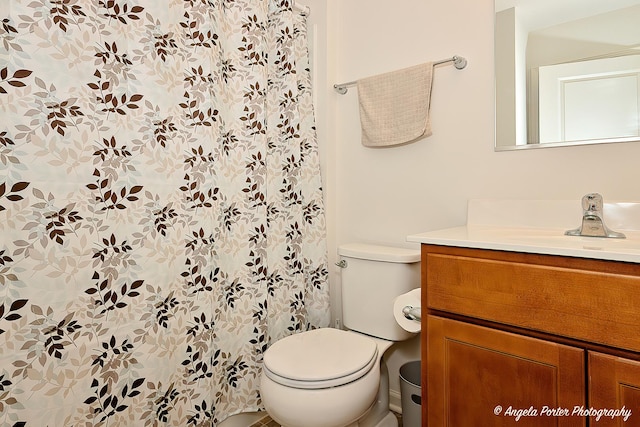 bathroom featuring vanity, curtained shower, and toilet
