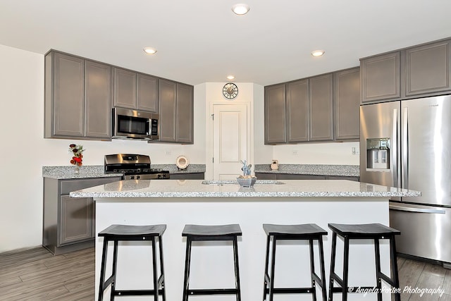 kitchen with stainless steel appliances, recessed lighting, a kitchen breakfast bar, and light wood-style floors