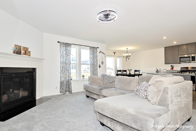 living room with carpet floors, baseboards, a notable chandelier, a glass covered fireplace, and recessed lighting