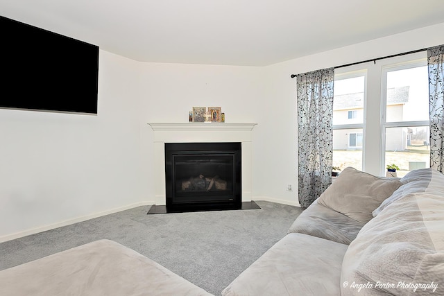 carpeted living area featuring baseboards and a fireplace with flush hearth