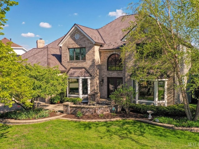 view of front of property with a front lawn, brick siding, and a chimney