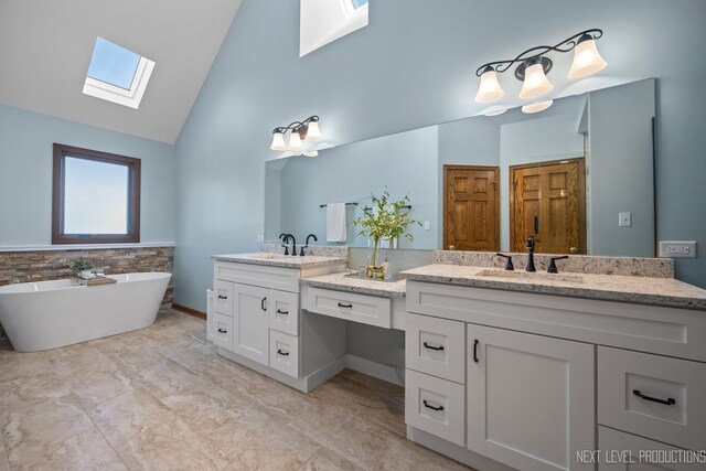 full bath with a skylight, double vanity, high vaulted ceiling, and a soaking tub