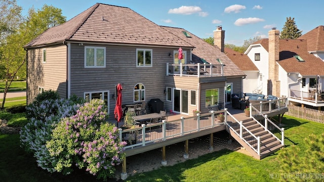 back of property featuring a balcony, a yard, a chimney, a deck, and outdoor lounge area