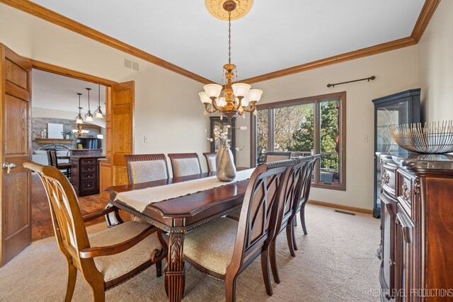dining room featuring a chandelier, light colored carpet, ornamental molding, and baseboards