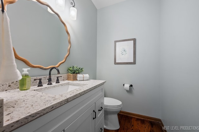 bathroom featuring wood finished floors, baseboards, toilet, and vanity