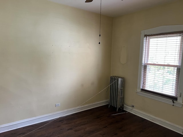 unfurnished room featuring radiator heating unit, dark wood finished floors, healthy amount of natural light, and baseboards