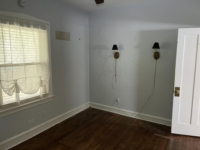 empty room with wood finished floors, plenty of natural light, baseboards, and a ceiling fan