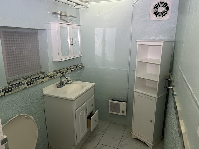 bathroom featuring marble finish floors, vanity, and heating unit