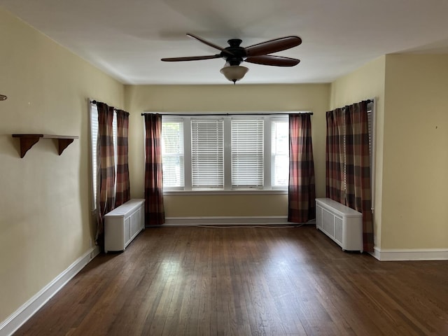 unfurnished room with radiator heating unit, ceiling fan, wood finished floors, and baseboards