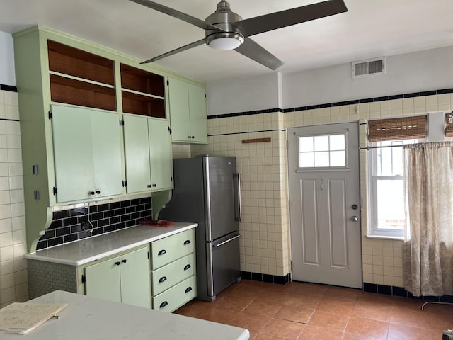 kitchen with freestanding refrigerator, ceiling fan, green cabinets, light countertops, and tile patterned flooring