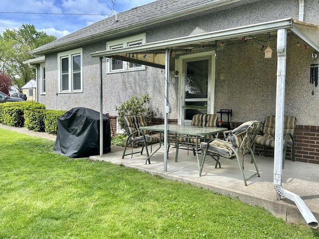 back of property with a lawn, a patio area, and stucco siding