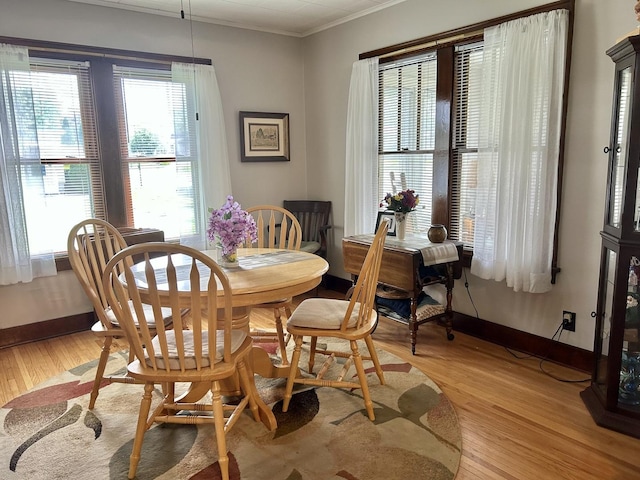 dining area with crown molding, light wood-style floors, and baseboards