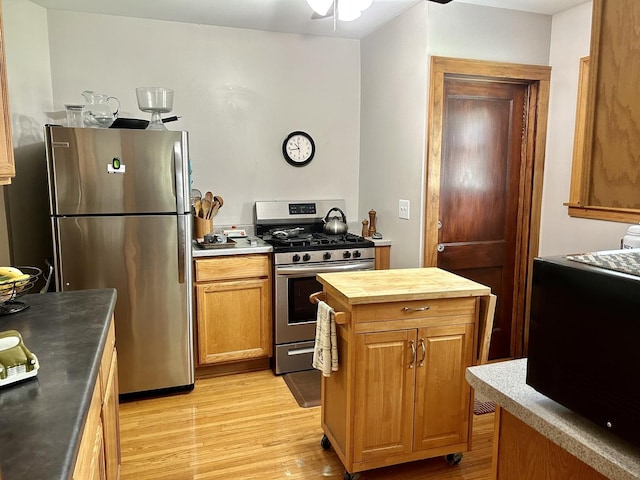 kitchen with stainless steel appliances, a ceiling fan, wooden counters, and light wood-style flooring