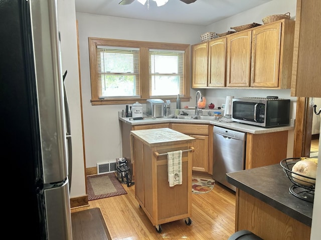 kitchen featuring a sink, stainless steel appliances, a ceiling fan, light wood-type flooring, and visible vents