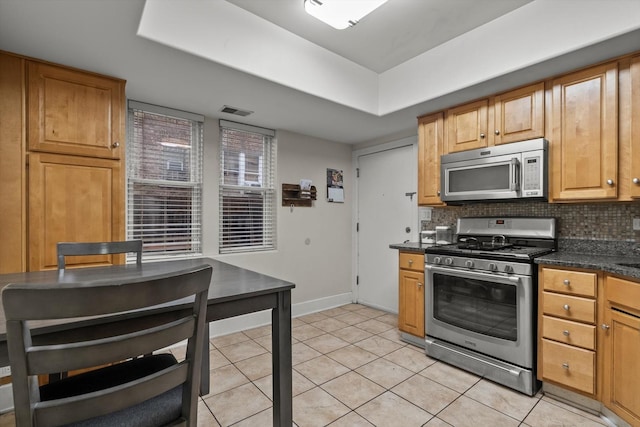 6401 23rd St Unit 2, Berwyn, IL 60402 - kitchen with backsplash, appliances with stainless steel finishes, dark countertops, light tile patterned floors, and baseboards