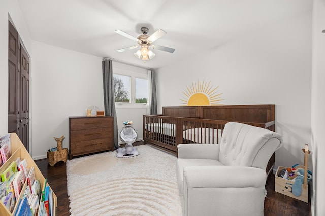bedroom featuring ceiling fan, a crib, wood finished floors, and a closet