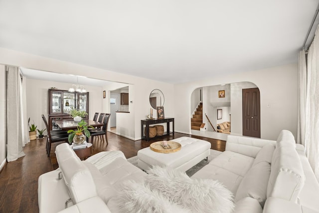 living room with an inviting chandelier, stairs, baseboards, dark wood-style floors, and arched walkways