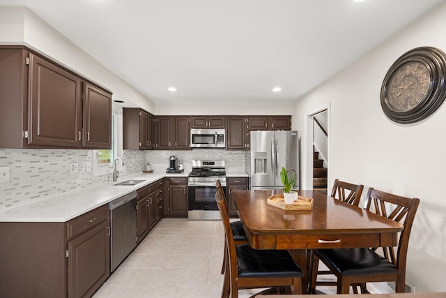 kitchen with decorative backsplash, dark brown cabinetry, a sink, light countertops, and stainless steel appliances