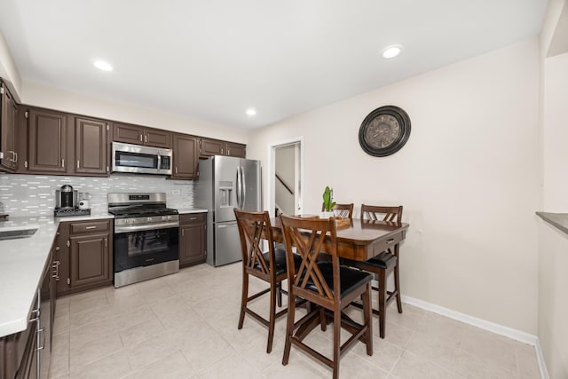 kitchen featuring light countertops, dark brown cabinetry, stainless steel appliances, and backsplash