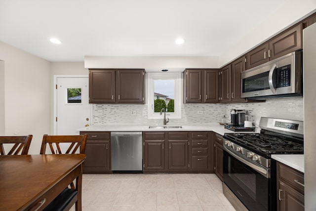 kitchen featuring decorative backsplash, appliances with stainless steel finishes, dark brown cabinets, a sink, and light countertops