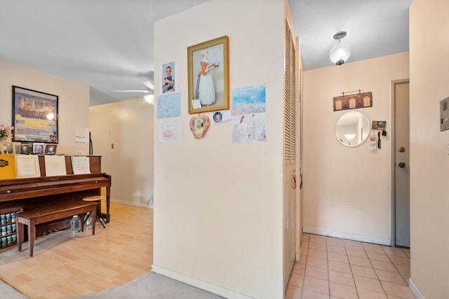 hall featuring light tile patterned flooring and baseboards