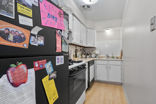 kitchen featuring freestanding refrigerator, a sink, white cabinetry, dishwashing machine, and range with gas cooktop