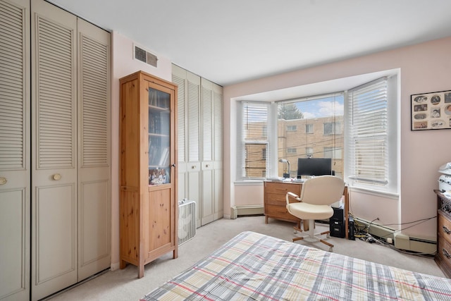 bedroom with light colored carpet, baseboard heating, visible vents, and two closets