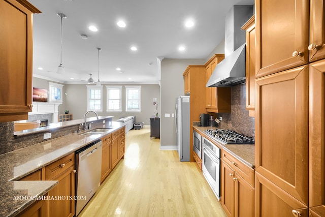 kitchen with crown molding, a ceiling fan, open floor plan, a sink, and appliances with stainless steel finishes