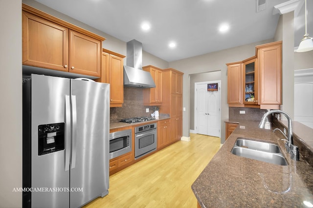 kitchen featuring visible vents, wall chimney range hood, tasteful backsplash, a sink, and appliances with stainless steel finishes