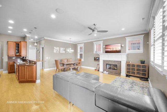 living area with ceiling fan, visible vents, crown molding, light wood finished floors, and a glass covered fireplace