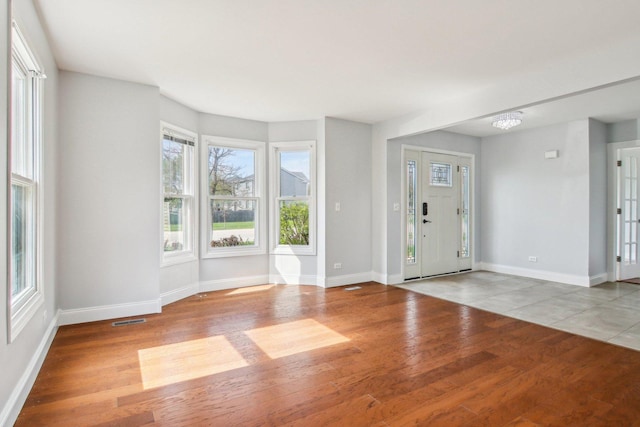 entryway with baseboards, visible vents, and wood finished floors