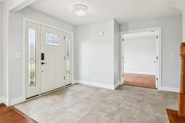 foyer with baseboards, light tile patterned flooring, and a chandelier