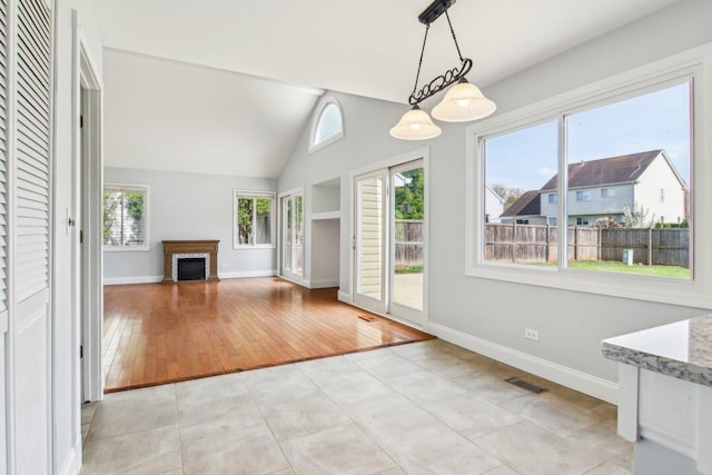 interior space featuring visible vents, baseboards, a fireplace, and high vaulted ceiling